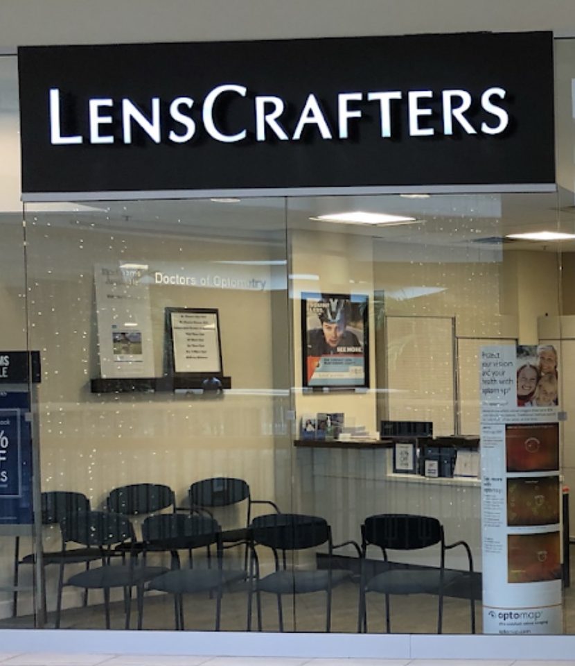 The LensCrafters storefront at Hamilton Mall, second level. The illuminated sign is above a glass frontage with a reception desk and waiting chairs inside.